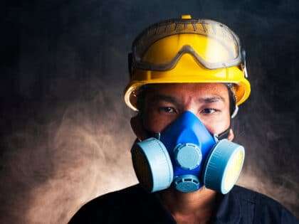 Gas,Mask.,Respirator,Cartridge.,Man,In,Factory,With,Backdrop,